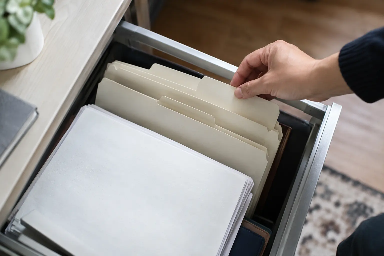 A hand retrieves reusable document materials from an office drawer.