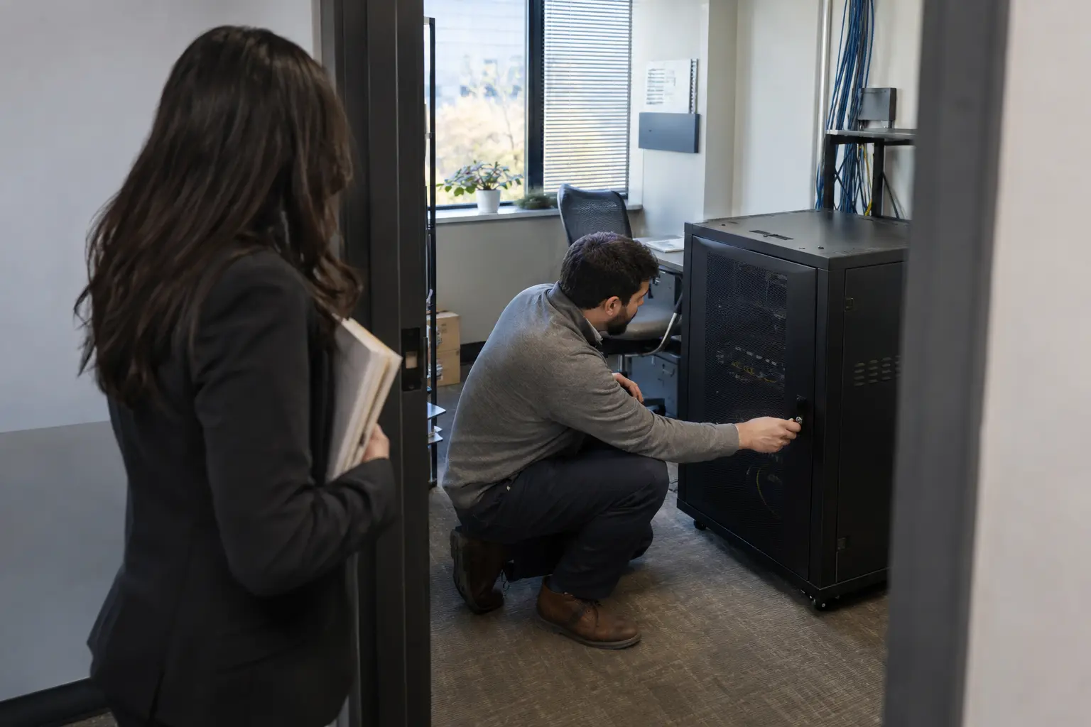 An administrator checks access to a secure office server cabinet.
