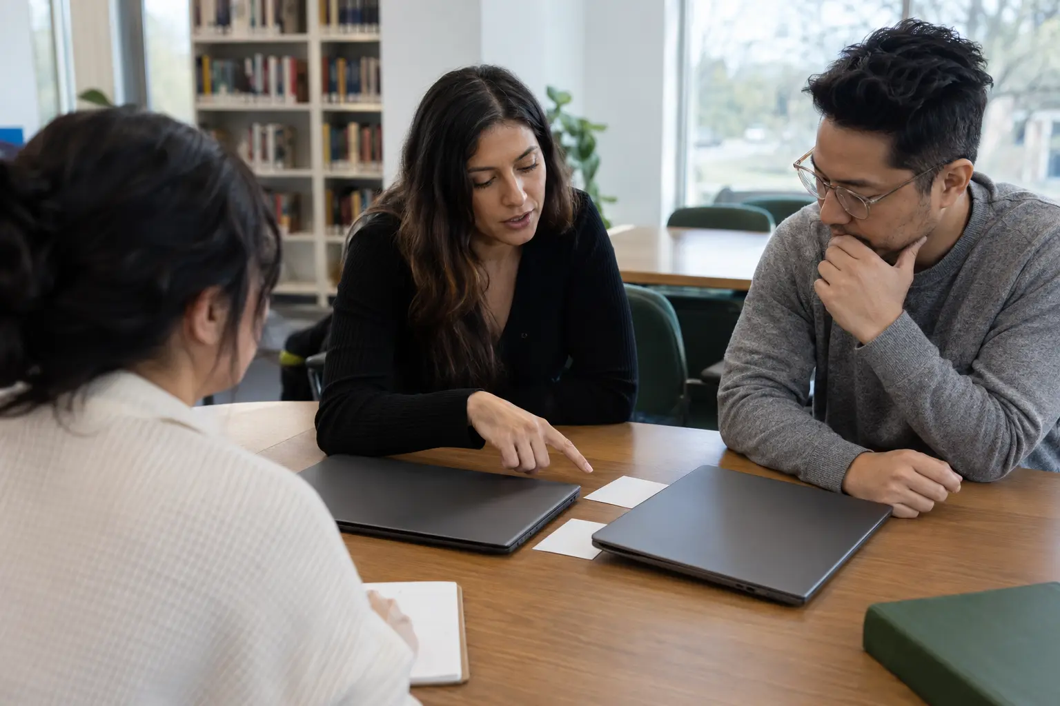 Colleagues compare work tools around a meeting table.